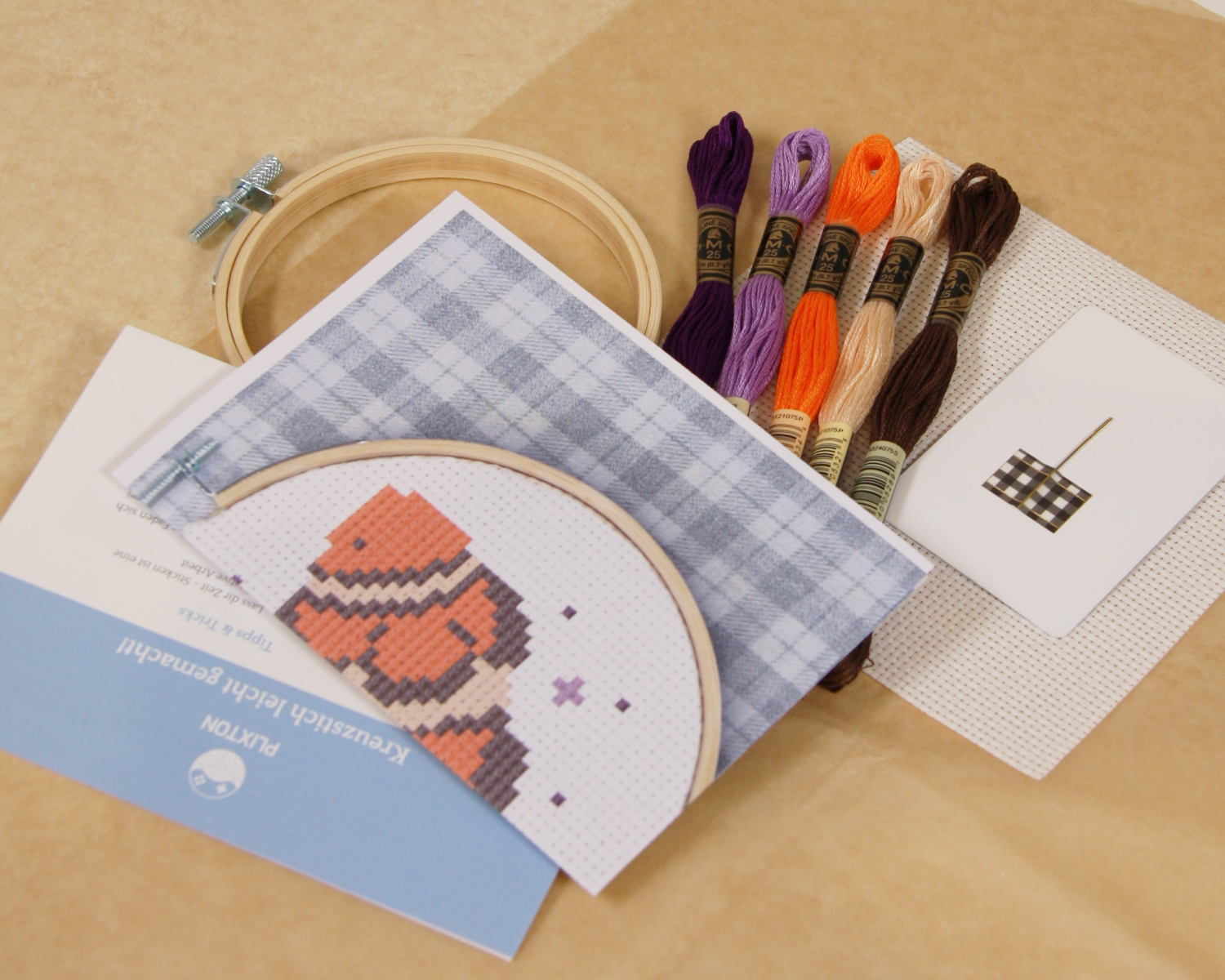 Inhalt des Clownfish & Sparkle Kreuzstichsets mit Stickgarn, Stoff, Vorlage und Holzrahmen.