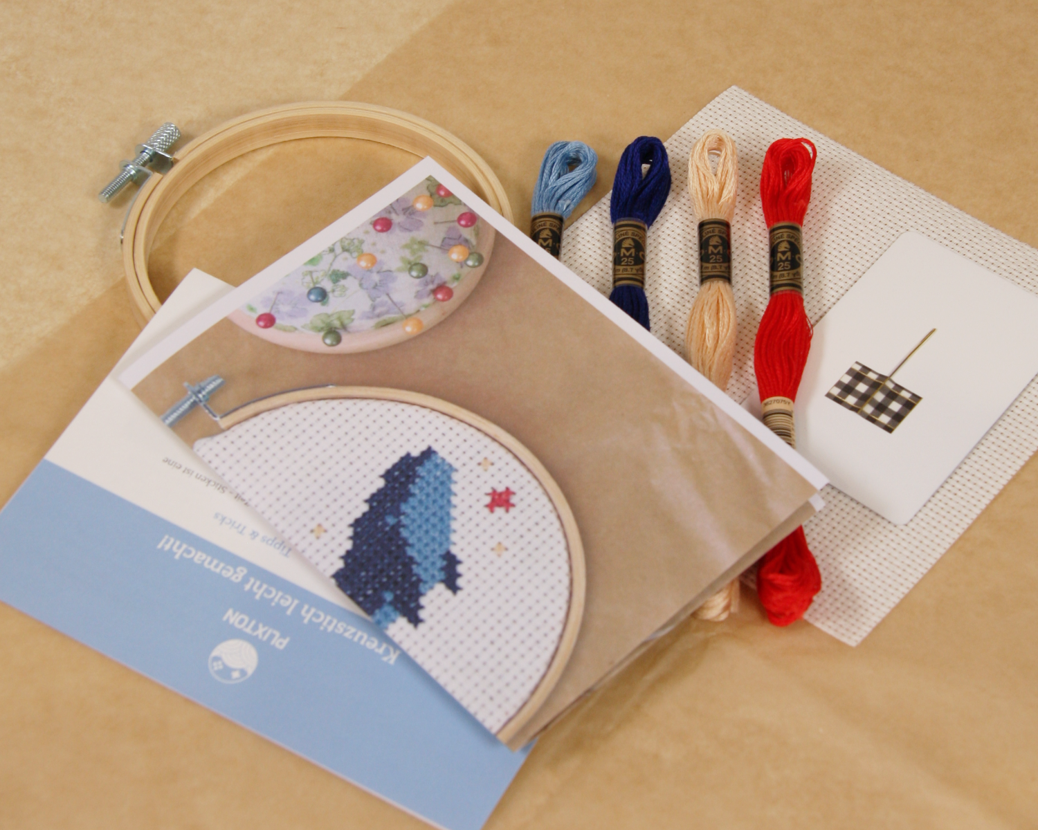 Inhalt des Whale & Sparkle Kreuzstichsets mit Stickgarn, Aida-Stoff, Stickvorlage und Holzrahmen.