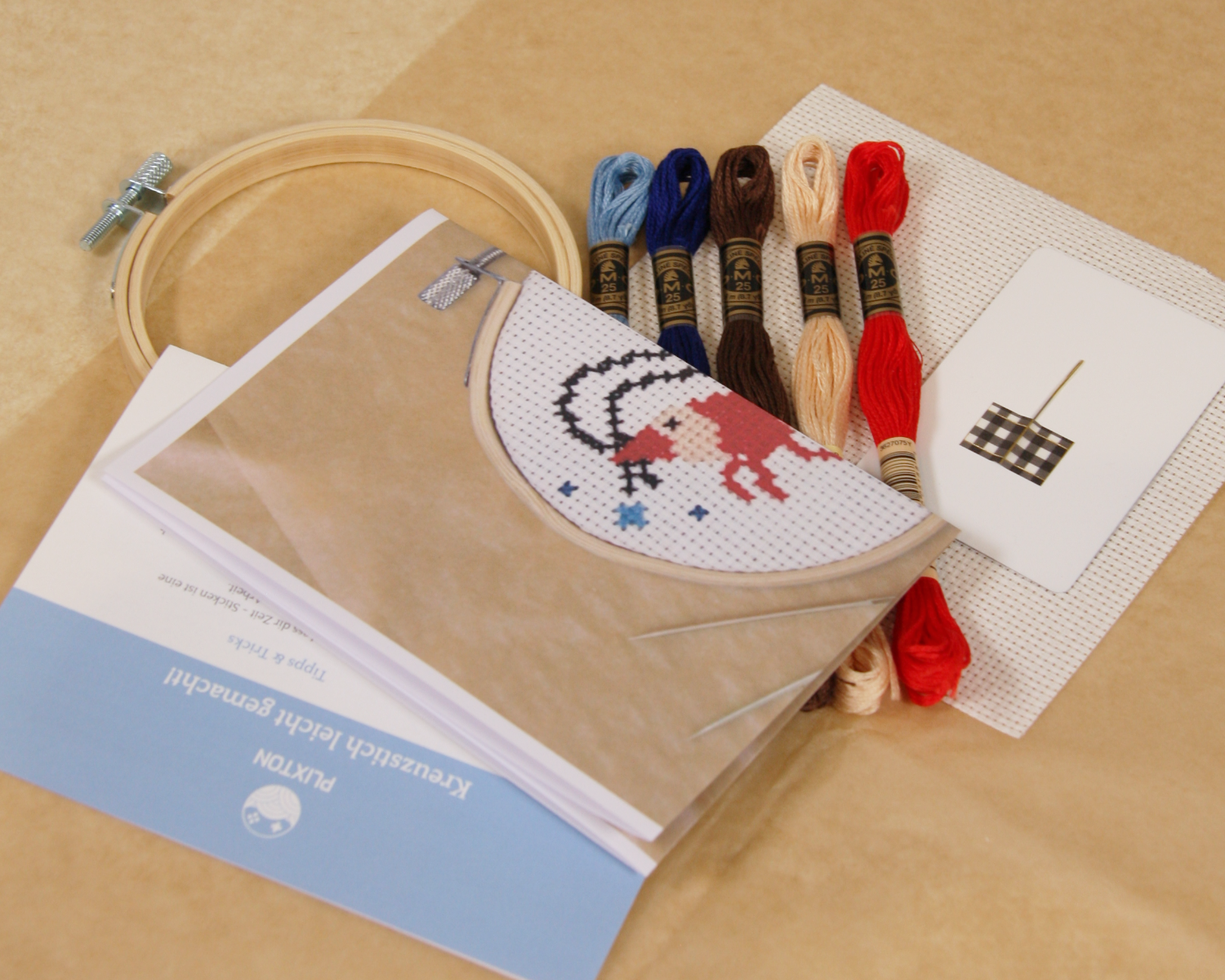 Inhalt des Shrimp & Sparkle Kreuzstichsets mit Stickgarn, Stoff, Vorlage und Holzrahmen.