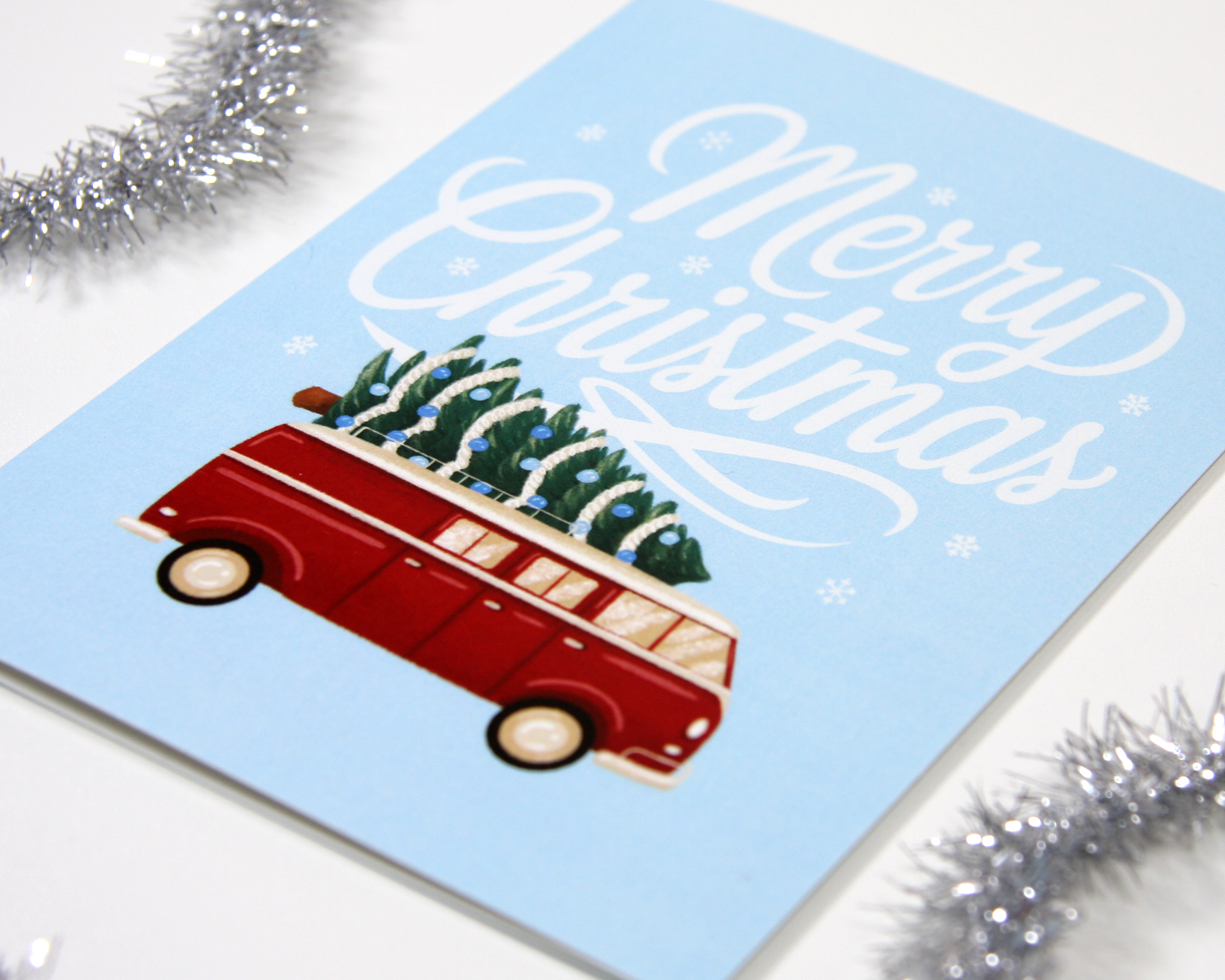 Weihnachtskarte mit rotem Bus, festliches Design mit Tannenbäumen und Schriftzug Merry Christmas